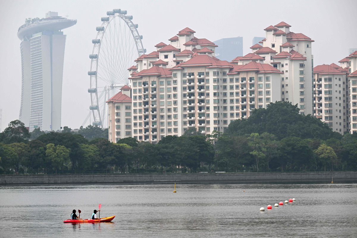 People row a canoe along the Kallang river as the haze eases in Singapore on October 23, 2026. (Photo by Roslan RAHMAN / AFP)