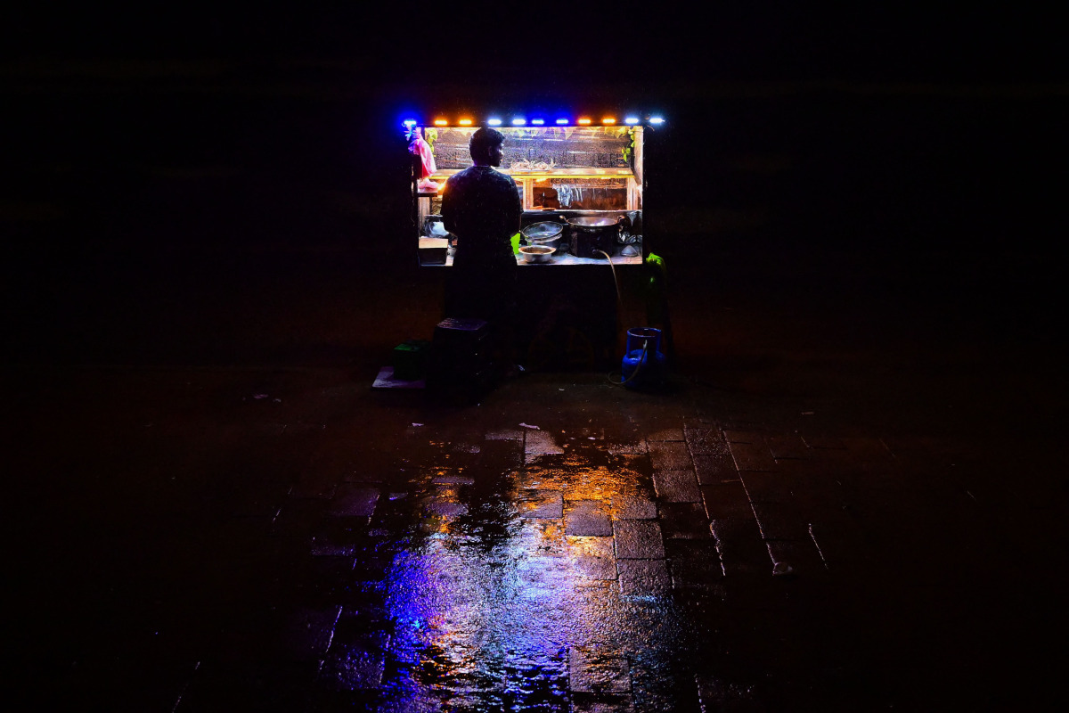 A vendor selling prawns waits for customers at the Galle Face seafront promenade, during a rainy night in Colombo on October 26, 2026. (Photo by Ishara S. KODIKARA / AFP)