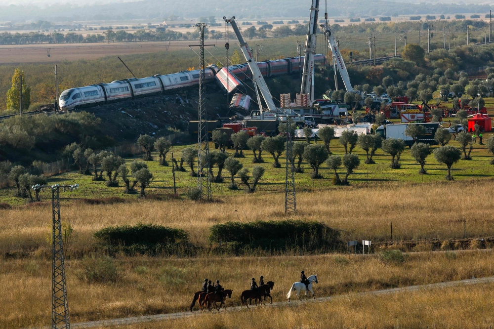 Spanish mounted police survey the perimeter around the damaged carriages of a train crash, a day after the accident on October 29, 2026. (Photo by Oscar Del Pozo / AFP)