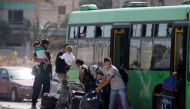 Syrian rebels and their families carry their luggage into a bus to evacuate the besieged Waer district in the central Syrian city of Homs, after a local agreement reached between rebels and Syria's army, Syria September 22, 2016. REUTERS/Omar Sanadiki 