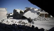 Men ride a motorcycle near damaged buildings in the rebel held Douma neighbourhood of Damascus, Syria September 22, 2016. REUTERS/Bassam Khabieh