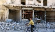 A boy sits on a bicycle in front of damaged shops after an airstrike on the rebel held al-Qaterji neighbourhood of Aleppo, Syria September 25, 2016. REUTERS/Abdalrhman Ismail