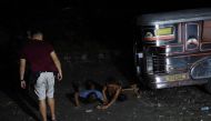 A police officer (L) in civilian clothes watches suspected drug users arrested during a drug buy-bust operation by police along a rail line in Caloocan City suburban Manila on early September 30, 2016. Philippine President Rodrigo Duterte on September 30 