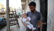 Syrian Yehya Maatouq holds his four-month-old daughter Wahida, whose rescue video posted online by the White Helmets went viral, in the northwest city of Idlib, on October 1, 2016. AFP / Omar haj kadour