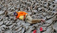 A farmer rests upon sacks filled with paddy at a wholesale grain market in Chandigarh, India, October 16, 2016. Reuters/Ajay Verma 