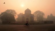 An Indian cyclist rides along a street as smog envelops a monument in New Delhi on October 31, 2016, the day after the Diwali festival. AFP / MONEY SHARMA