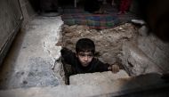 A Syrian boy climbs out of Abu Omar's shelter in the rebel-held town of Douma, on the eastern outskirts of Damascus, on October 30, 2016.  AFP / Sameer Al-Doumy