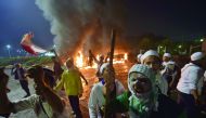 Indonesian protesters react as police shoot tear gas next to two burned cars outside the presidential palace in clashes that marred an otherwise peaceful rally against governor Basuki Tjahaja Purnama, a Christian accused of insulting Islam, in Jakarta on 