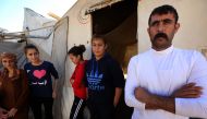 Ali Mahmud (R), a displaced Iraqi man from the Yazidi community who fled violence between Islamic State (IS) group jihadists and Peshmerga fighters in the northern town of Bashiqa, stands with family members outside a tent at a camp for internally displac