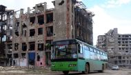 A bus, with Syrians from various western districts on board, drives past damaged buikdings in Aleppo's government-held Shihan neighbourhood during a bus trip through government-held territory between the two sides of the divided city on December 3, 2016. 