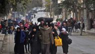 Syrian residents of eastern rebel-held parts of Aleppo walk through the Kadi Askar district as they leave their homes for a safer place in a distinct rebel-controlled area on November 30, 2016, during a Syrian army offensive on the eastern sectors of the 