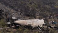 Pakistani sit beside the wreckage of the crashed PIA passenger plane Flight PK661 near the village of Saddha Batolni in the Abbottabad district of Khyber Pakhtunkhwa province on December 8, 2016. AFP / AAMIR QURESHI