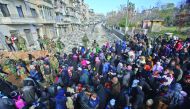 Syrian residents fleeing the violence gather at a checkpoint, manned by pro-government forces, in the Maysaloun neighbourhood of the northern embattled city of Aleppo