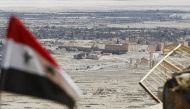 A Syrian national flag flutters as the ruins of the historic city of Palmyra are seen in the background, in Homs Governorate, Syria April 1, 2016. REUTERS/Omar Sanadiki/File Photo