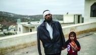 An injured man who just arrived on the Syrian side of the Bab Al Hawa border waits with his child outside a hospital, yesterday.