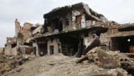 A Syrian man sits on the rubble of his house in Aleppo's Al-Arkoub neighbourhood on December 17, 2016, after pro-government forces retook the area from rebel fighters. / AFP / Youssef KARWASHAN