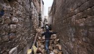 A Syrian boy makes his way through the rubble of destroyed buildings as he heads to his house in Aleppo's Dahret Awad neighbourhood on December 17, 2016, after pro-government forces retook the area from rebel fighters. / AFP / Youssef KARWASHAN