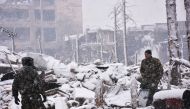 Syrian pro-government forces walk as snow falls in Aleppo on December 21, 2016. The last residents hoping to leave rebel-held Aleppo waited in the snow as delays hit an evacuation that will leave Syria's army in full control of the devastated city. AFP / 