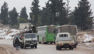 Vehicles carrying Syrians who are being evacuated from the rebel-held Shiite majority towns of Fuaa and Kafraya (R) into government controlled area, and others leaving Aleppo towards rebel-held territory (L), cross each on the road in a rebel-held territo
