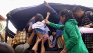 Residents are assisted into a truck after the local government implemented preemptive evacuations at Barangay Matnog, Daraga, Albay province on December 25, 2016, due to the approaching typhoon Nock-Ten. Babies, toddlers and old people were loaded onto mi