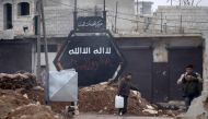 A boy carries a water container near a sign that used to belong to ISIS in al-Rai town, northern Aleppo countryside, Syria December 25, 2016. (REUTERS/Khalil Ashawi).
