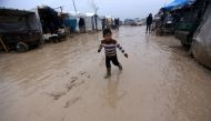 An internally displaced Syrian boy walks over rainwater in the Bab Al-Salam refugee camp, near the Syrian-Turkish border, northern Aleppo province, Syria December 26, 2016. REUTERS/Khalil Ashawi