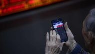 An investor uses a mobile phone to check stock indexes at a securities company in Beijing on January 3, 2017. AFP / WANG Zhao
