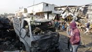 Iraqis inspect the site of an attack at Baghdad's main vegetable market on January 8, 2017. A suicide bomber blew up a car at the entrance of the market, killing at least 11 people and wounding dozens, security officials and medics said. / AFP / SABAH ARA