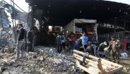 Iraqis salvage vegetables from the site of an attack at Baghdad's main vegetable market on January 8, 2017. A suicide bomber blew up a car at the entrance of the market, killing at least 11 people and wounding dozens, security officials and medics said. /