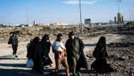 Iraqis walk past an Islamic State (IS) group sign in the newly liberated part of eastern Mosul on January 17, 2017, during an ongoing military operation against the jihadists.   AFP / Dimitar DILKOFF
