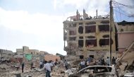 People react and walk among rubbles following an attack outside an hotel on January 25, 2017, in Mogadishu. At least seven people were killed after two car bombs exploded outside a popular Mogadishu hotel and gunmen forced their way inside the building an