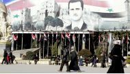 Syrians walk past a poster of Syrian President Bashar al-Assad in Aleppo's Saadallah al-Jabiri Square on January 22, 2017, a month after Syrian government forces retook the northern city from rebel fighters. AFP / Louai Beshara