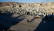 A civilian rides a bicycle past a cemetery in the rebel held besieged Douma neighbourhood of Damascus, Syria January 3, 2017. REUTERS/Bassam Khabieh