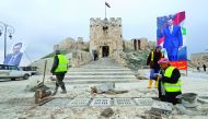 Workers repair the damage in front of Aleppo's historic citadel, as posters depicting Syria's President Bashar Al Assad are erected in the Old City of Aleppo, yesterday.