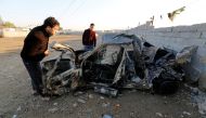 Men look at the wreckage of a burnt car after a suicide bomber detonated a pick-up truck on Wednesday in Sadr City, a heavily populated poor Shi'ite suburb of Baghdad, Iraq, February 16, 2017. REUTERS/Wissm al-Okili