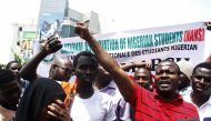 Nigerian students shout slogans against South Africa as they protest outside the South African Digital Satellite TV's (DSTV) Nigerian headquarters in Abuja against the recent spike in attacks targeting foreign nationals in South Africa on February 23, 201