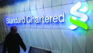 A pedestrian walks past a Standard Chartered sign in the Central district of Hong Kong.