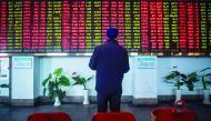 An investor looks at an electronic board showing stock information at a brokerage house in Shanghai.