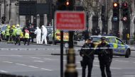 Armed police officers carry their weapons as forensics officers work near a grey vehicle that crashed into the railings of the Houses of Parliament in central London on March 22, 2017, during an emergency incident. AFP / Daniel LEAL-OLIVAS
