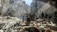 A Syrian mourns as members of the Syrian civil defence volunteers, also known as the White Helmets, and people search for survivors from the rubble following reported air-strikes on the rebel-held town of Saqba, in Eastern Ghouta, on April 4, 2017. / AFP 