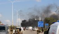 A picture taken on April 15, 2017, shows smoke billowing following a suicide car bombing in Rashidin, west of Aleppo, that targeted buses carrying Syrians evacuated from two besieged government-held towns of Fuaa and Kafraya.  AFP / Ibrahim YASOUF
