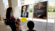 French citizens residing in Lebanon look at the election posters of independent centrist French presidential candidate Emmanuel Macron (L) and far-right Front National (FN - National Front) candidate Marine Le Pen, as they arrive to cast their votes at th