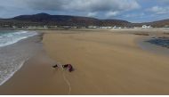 A woman walks her dogs along Dooagh beach after a storm returned sand to it, 30 years after another storm had stripped all the sand off the beach, on Achill island, County Mayo, Ireland, May 5, 2017. Picture taken May 5, 2017. MANDATORY CREDIT Sean Molloy