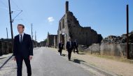 French President Emmanuel Macron (L) walks with officials after a ceremony to commemorate the 73rd anniversary of the Oradour-sur-Glane massacre, in the ruins of the martyrs village of Oradour-sur-Glane on June 10, 2017. (AFP / POOL / STEPHANE MAHE)