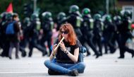 A protestor plays the flute as German police walk behind, at a demonstration during the G20 summit in Hamburg, Germany, July 7, 2017. REUTERS/Hannibal Hanschke

