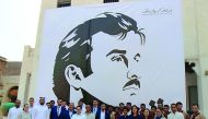 The management and staff of Souq Waqif Boutique Hotels in front of the mural of Emir H H Sheikh Tamim bin Hamad Al Thani. 