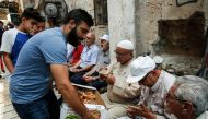 A Palestinian distributes pastries donated to support demonstrators who have kept vigil for over a week as they pray outside Al-Aqsa mosque compound in the old city of Jerusalem on July 26, 2017. AFP / Ahmad Gharabli