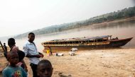 This file photo taken on July 28, 2017 shows people standing next to an empty boat as the traffic on the Kasai river has been slowed down due to insecurity at the port of Tshikapa, Democratic Republic of Congo. AFP / Junior D. Kannah