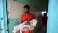 An Indian relative holds the body of a child while walking out of Baba Raghav Das Hospital in Gorakhpur, in the northern Indian state of Uttar Pradesh, on August 13, 2017. AFP / Sanjay Kanojia