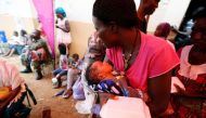 A mother, with her baby, picks up food at the internally displaced persons camp in Regent, Sierra Leone August 19, 2017. Reuters/Afolabi Sotunde